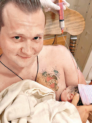 紐鮑爾戴上餵奶輔助裝置，代妻子餵哺女兒。（互聯網圖片）