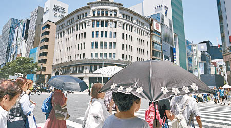 東京民眾在烈日下打傘出外。（美聯社圖片）
