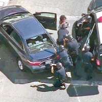 有警員擎槍指向超市，並從一輛汽車帶走一名乘客。（美聯社圖片）