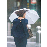 東京狂風暴雨，民眾撐傘外出。（美聯社圖片）
