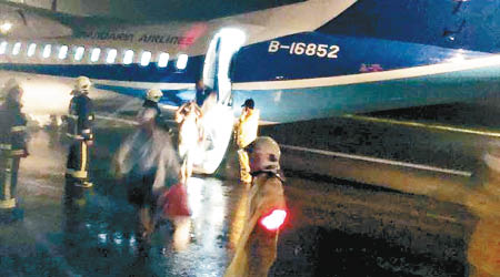 乘客冒雨離開涉事客機。（互聯網圖片）