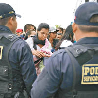 警員檢查委內瑞拉難民的護照。（美聯社圖片）
