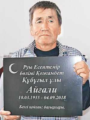 蘇普加利耶夫抱着自己的墓碑拍照。（互聯網圖片）