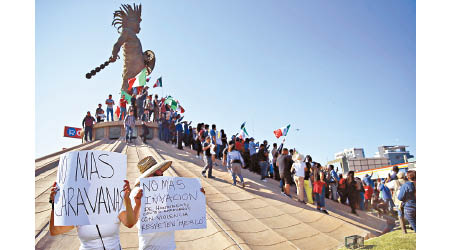 民眾高舉墨西哥國旗，抗議中美洲難民陸續抵達。（美聯社圖片）