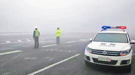 青島大霧籠罩，交警在高速公路指揮交通。（互聯網圖片）