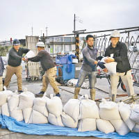 工人沿岸堆沙包防水浸。（美聯社圖片）
