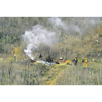 直升機墜毀現場冒煙。（美聯社圖片）