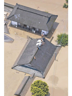熊本縣人吉市市內嚴重水浸，居民逃上屋頂避災。（美聯社圖片）