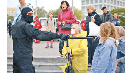 蒙面警員（左）與女示威者爭論。（美聯社圖片）