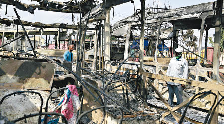 尼日利亞示威不斷，一輛巴士燒至只餘下支架。（美聯社圖片）