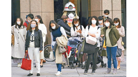 民眾繼續戴上口罩防疫。（美聯社圖片）