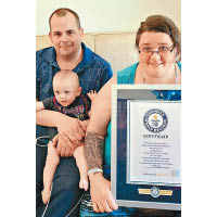 哈欽森打破世界紀錄，父母高興地帶同證書與愛兒合照。