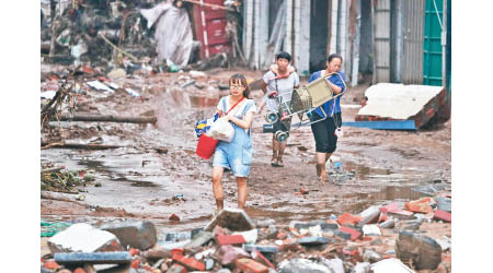 鞏義市民眾在滿是泥濘的街道上搬走物資。（中新社圖片）