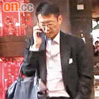 許晉亨挽着公事包，木無表情講電話。