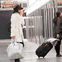 木村乃換上白色大褸拿着行李轉乘機鐵。