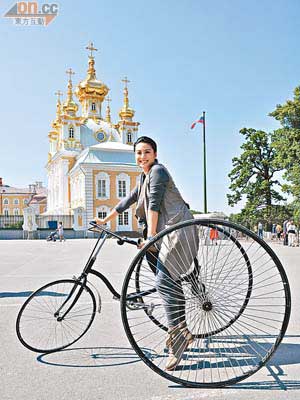 廖碧兒踏着巨轆單車，於彼得夏宮前留影。