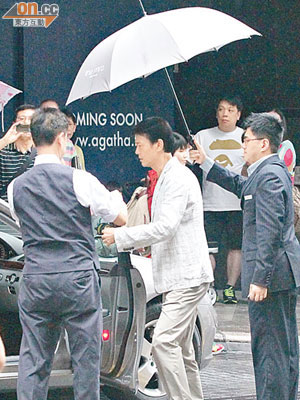 秋官準備登上座駕時遇下雨，有人為他打傘。