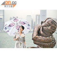 嘉玲撐「傻笑人」雨傘，與雕塑合照。