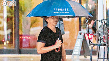 林子祥拿着雨傘前往開餐。