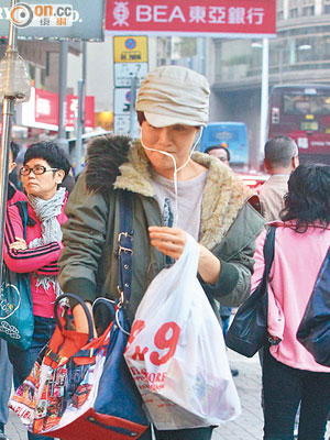 梁嘉琪挽着大袋戰利品，情急下只好咬實hand free講電話。