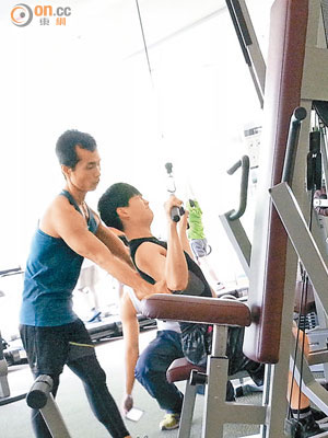 胡鴻鈞在肌男協助下健身。