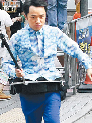 王祖藍腰間繫上環迴攝錄機，於馬路拍攝。