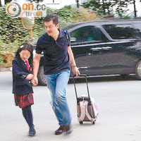 拖着書包的李亞鵬帶李嫣跑過馬路前往學校。