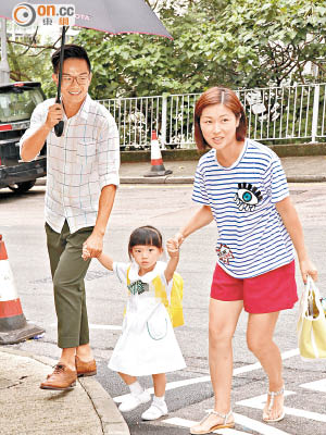 胡諾言撐着傘送老婆陳琪及囡囡入學校。