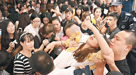 有女歌迷在混亂中被擠擁暈倒，需由保安抬離場。（CFP圖片）