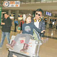 鍾幗坐在阿B所推的行李車上，向記者說新年快樂。