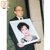 修哥長子胡永康捧着媽媽的遺照。