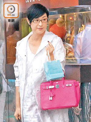 一身白色裝束的陳法蓉，挽着戰利品步出珠寶店。