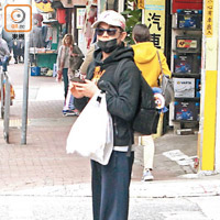 城城戴晒Cap帽、口罩及黑超，化身外賣仔在街頭等的士。