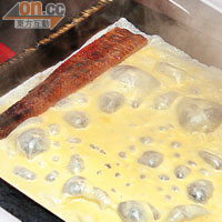 部分蛋漿倒入鑊中煎成班戟狀，並將鰻魚置在蛋皮邊緣。