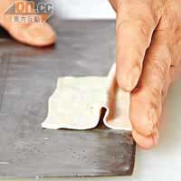 先將方形的豆腐乾橫切成薄片，彭師傅沒有度尺，但每片的厚薄都很一致。