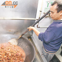 聯哥用大鐵鑊及大鐵鏟烹調南乳豬肉，這鑊可煮65斤豬肉，足夠200多人食。