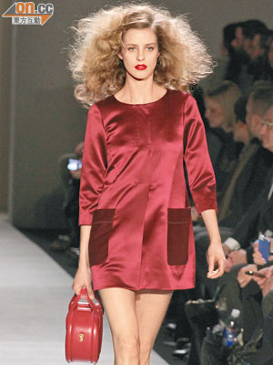 以色丁為衣料的紅色迷你連身裙，剪裁簡潔，兩個大口袋搶眼，有特色。