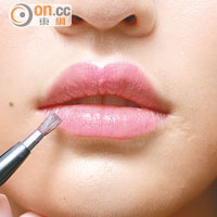 依唇形塗抹粉紅色唇膏，唇角及唇山等位置以唇掃修飾。
