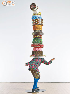 Yinka Shonibare MBE （RA）《Cake Kid》<br>真人比例的人物雕塑，背上頂着色彩繽紛、搖搖欲墜的蛋糕群，藝術家希望藉此表達人類在掙扎求存的過程中，不自覺地變得貪婪。（藝術門，1D09）