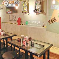 餐廳的牆上掛滿裝飾，包括寫上韓文的告示牌、安全衣、消防栓和鎢絲燈設計的LED燈。
