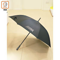 M雨傘<br>直徑120cm，黑色布面印有光面M廠徽，特別注入碳纖手柄，散發型格魅力。雙層布料，遮光和隔熱性高。布面施有Teflon塗層，具不錯的跣水效果，遮陰擋雨最在行。<br>售價：$860