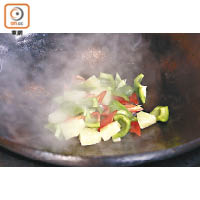 起油鑊將青紅椒及菠蘿炒香，加糖調味後炒勻撈起備用。