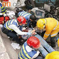 龍富路貨櫃車翻側，消防員與救護員將受傷司機救出。（黃君堡攝）