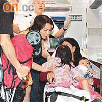 太古城兩名女童於扶手電梯跌倒受傷，由親人抱着送上救護車。	（蔡高華攝）