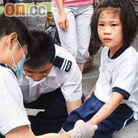 女童被玻璃碎片割傷手腳及前額，由救護員替她包紮。	（馬竟峰攝）