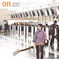 遊客減少，機場冷清清，清潔女工戴上口罩打掃地方。