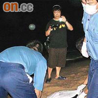 長洲東灣海邊發現的老翁屍體，由消防員移上岸。	（黃子源攝）
