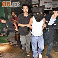 涉案南亞裔男子被拘捕，由警員蒙頭押走。（趙健圖攝）