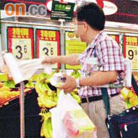 一名中年男子手持數盒紙包飲品進入超市，在水果貨攤取去數個保鮮袋。