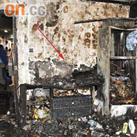 電視機着火的單位嚴重焚毀，放電視機的地櫃（箭嘴示）亦毀爛。	（李少雄攝）